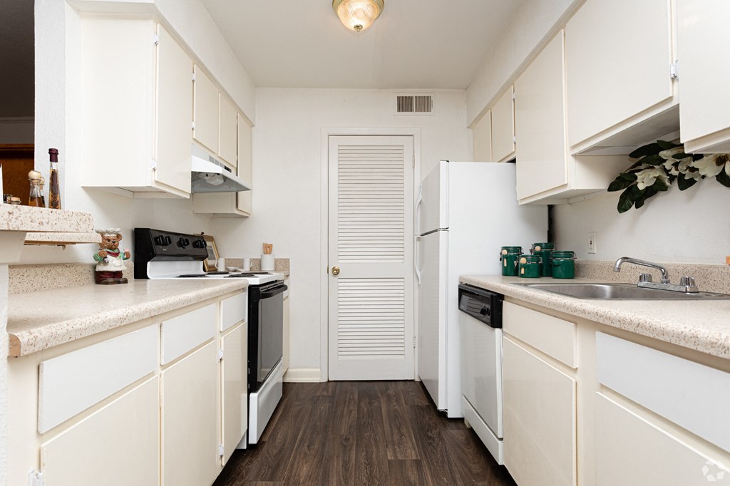 a kitchen with white cabinets and black appliances and a white door