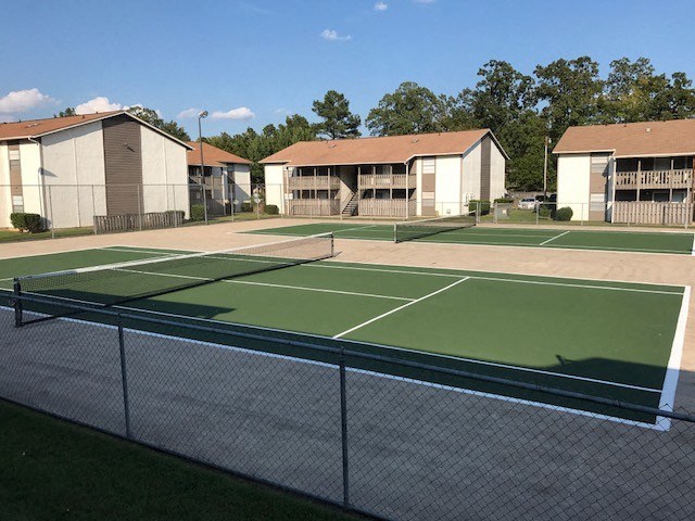 a tennis court with apartments in the background