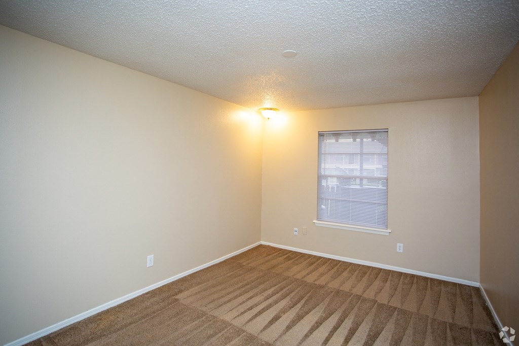 an empty room with a window and a carpet