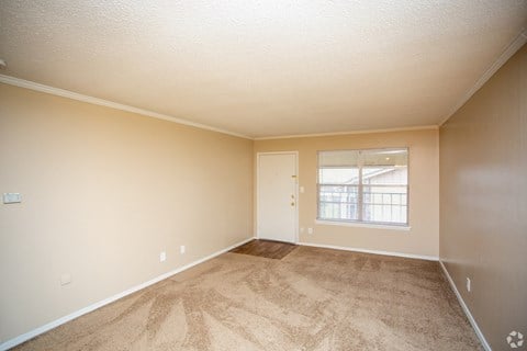 an empty living room with carpet and a window