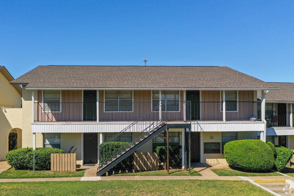 the front of a condo building with a deck and a staircase