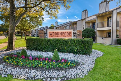 A sign that says Woodmeade Apartment Homes in front of a building.