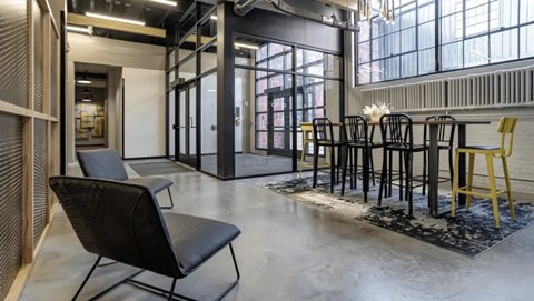 A black chair is in the foreground of a room with a table and chairs in the background.