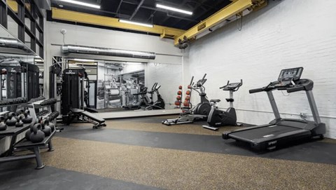 A gym with a variety of equipment including treadmills, weights, and exercise machines.