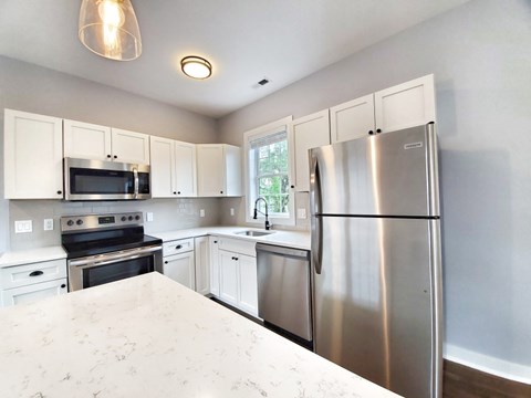 A kitchen with a refrigerator, oven, and microwave.