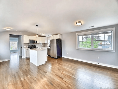 A kitchen with white cabinets and a wooden floor.