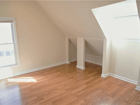 A room with wooden flooring and white walls.