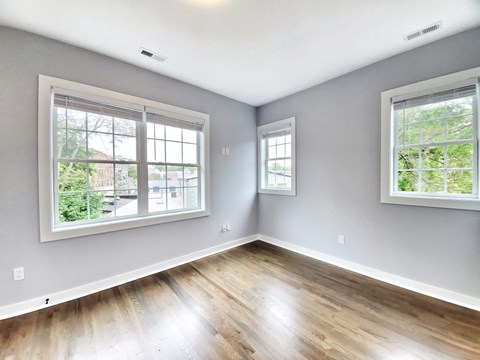 A room with two windows and wooden flooring.