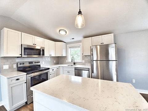 A kitchen with a stainless steel refrigerator and white cabinets.