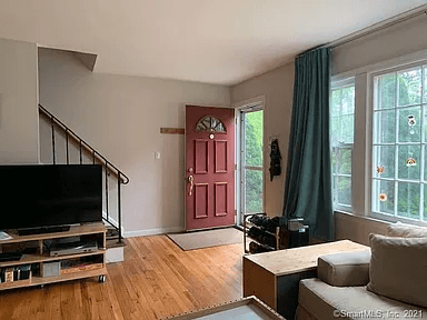A living room with a red door and a flat screen TV.