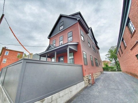 A red brick house with a black roof and a grey garage door.