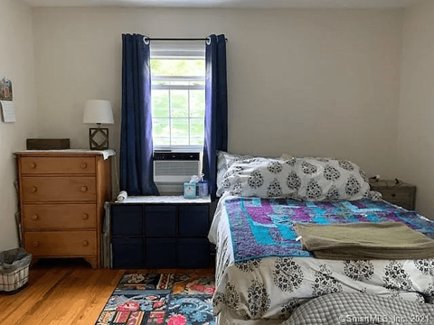 A bedroom with a bed, dresser, and window.