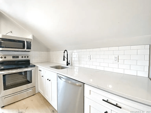 A kitchen with white cabinets and a stainless steel dishwasher.