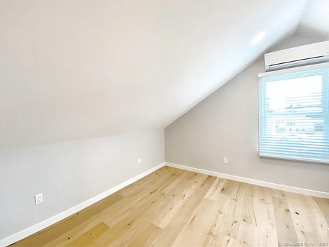 A room with wooden flooring and a window with blinds.