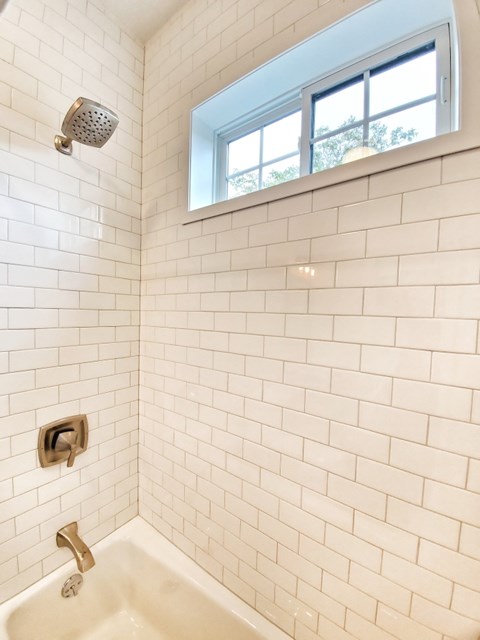 A white tiled bathroom with a window.