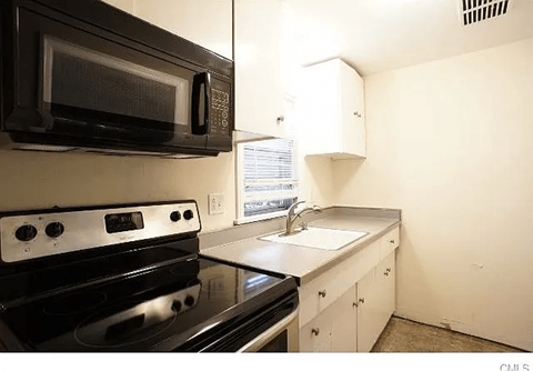 A black microwave oven is mounted above a black stove in a kitchen.