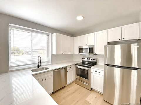 A modern kitchen with stainless steel appliances and white cabinets.