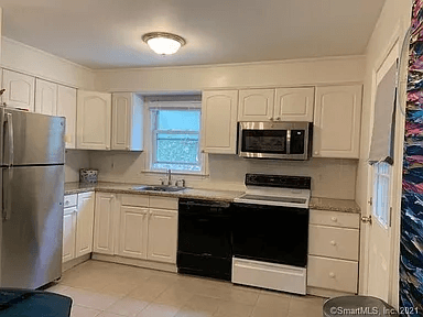 A kitchen with white cabinets and a black dishwasher.