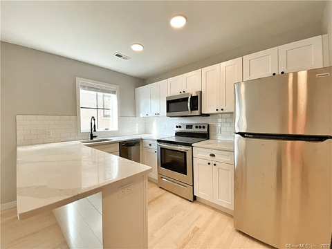 A modern kitchen with stainless steel appliances and white cabinets.