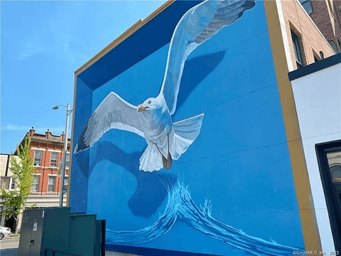 A large blue and white mural of a bird on a building.
