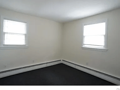 A room with two windows and a black floor.