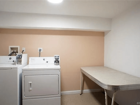 A laundry room with a washer and dryer and a table.