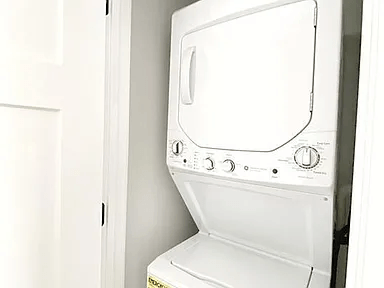A white dryer is sitting in a white closet.