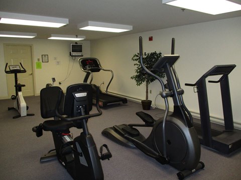A gym with a treadmill, elliptical trainer, and stationary bike.