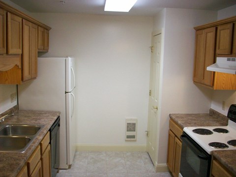A kitchen with a white refrigerator and brown cabinets.