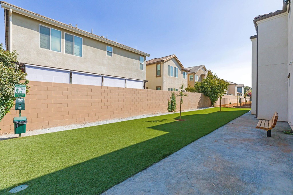 a yard with green grass and a bench in front of a building