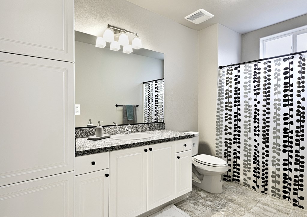 a bathroom with a black and white shower curtain and a toilet