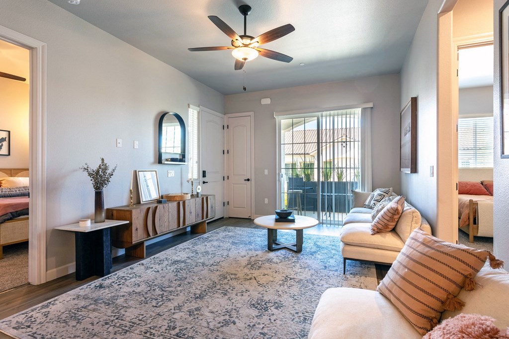 a living room with a ceiling fan and a door to a balcony