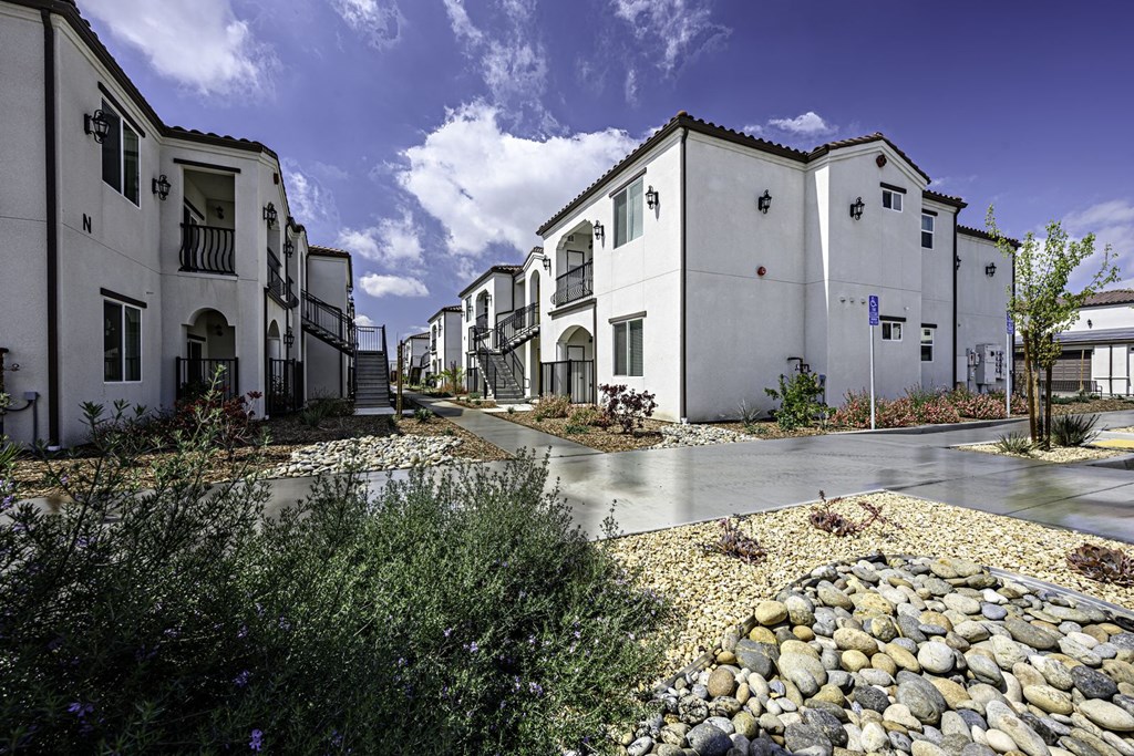 a row of white houses with gravel and trees