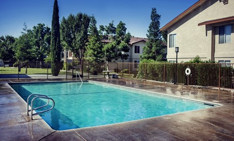 a pool with a fence around it and a house in the background