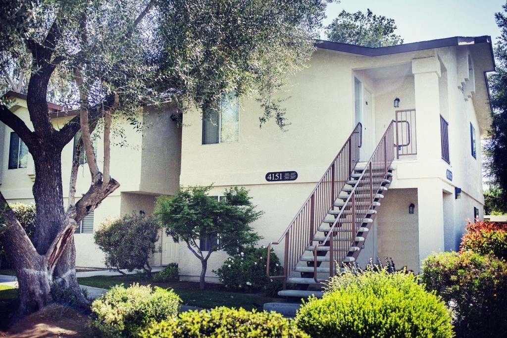 a house with a staircase and trees in front of it