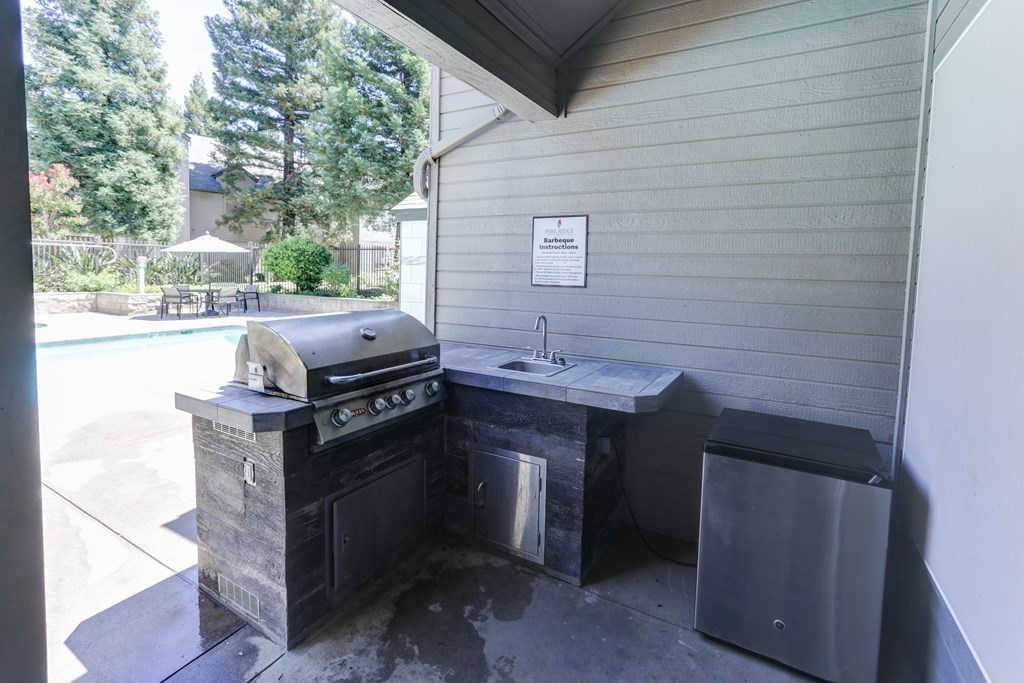 A black outdoor kitchen with a grill and sink.