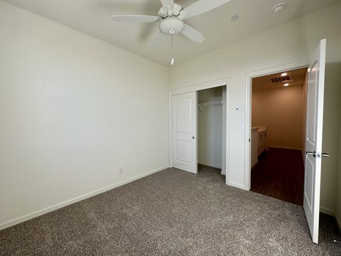 a bedroom with a ceiling fan and a door to a closet