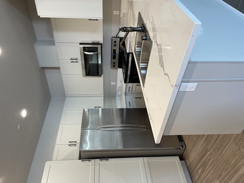 an updated kitchen with stainless steel appliances and marble counter tops