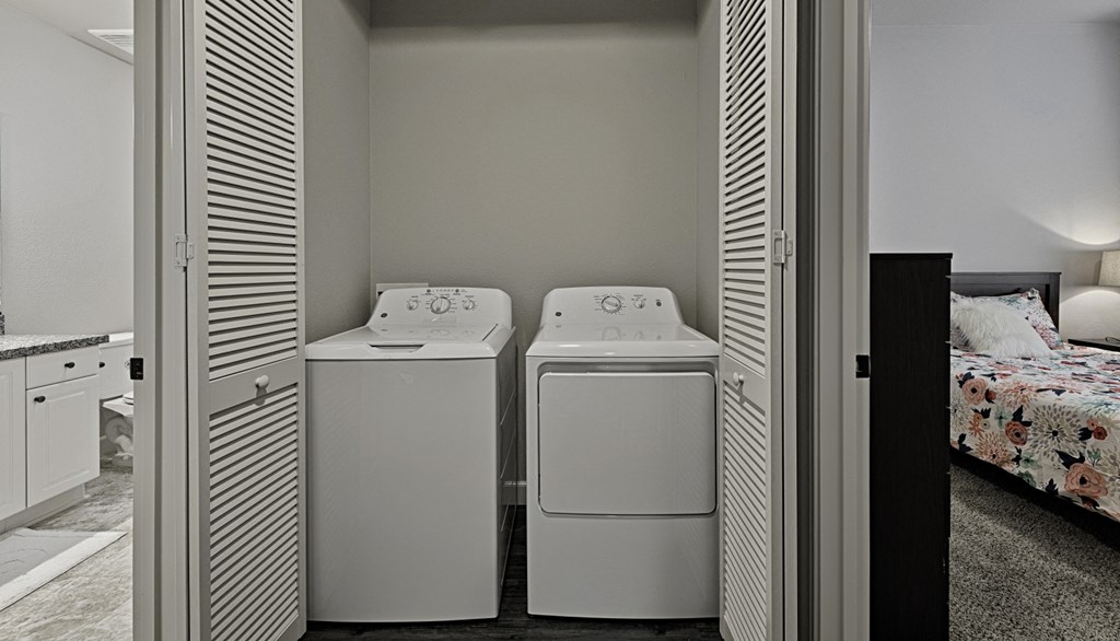 a laundry room with two washers and a dryer next to a bed