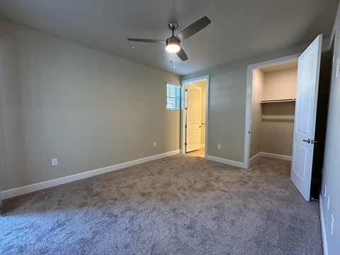 A room with a ceiling fan and carpeted floor.