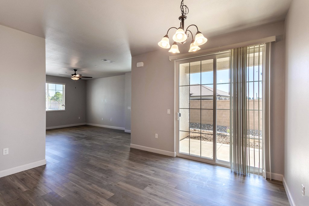 an empty living room with a glass door and a chandelier
