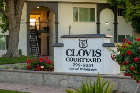 The entrance to Clovis Courtyard with a sign and flowers.