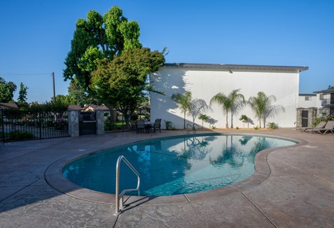 A pool with a diving board in front of a white building.