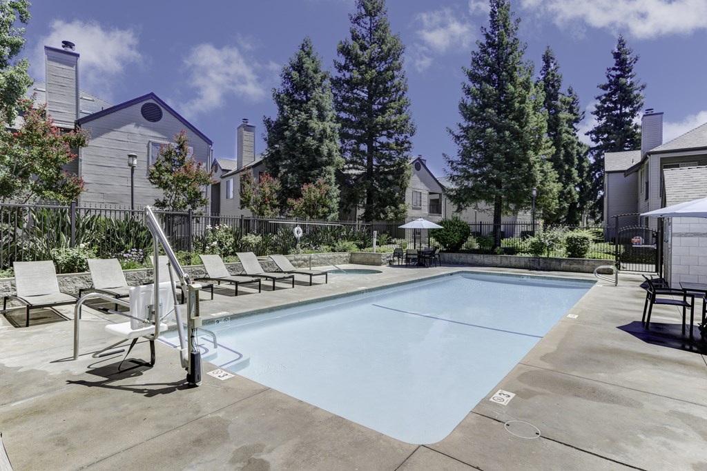 A swimming pool surrounded by lounge chairs and trees.