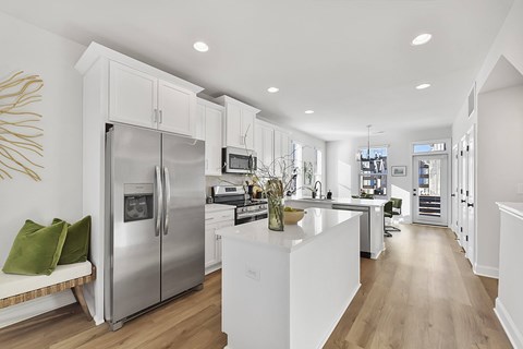 A modern kitchen with a stainless steel refrigerator and white cabinets.