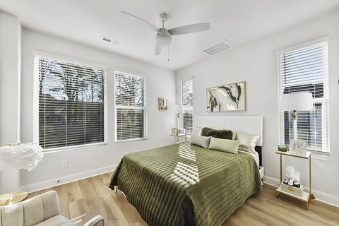 A bedroom with a bed, chair, and a ceiling fan.