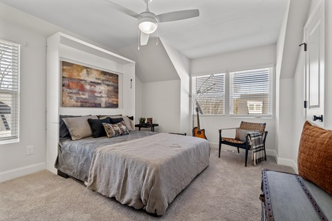 A bedroom with a large bed and a ceiling fan.