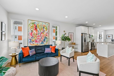 A living room with a blue couch and a large painting on the wall.