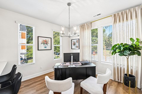 A room with a desk, chairs, and a potted plant.
