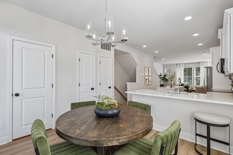 A dining room with a wooden table and green chairs.